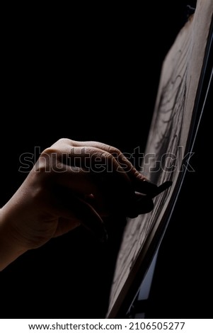 Artist drawing with chalk. Abstract hand painting on paper against black background.