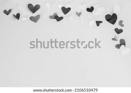 Valentines Day or wedding, invitation, scattered painted small cut out folded black and white hearts on white canvas background, copy space