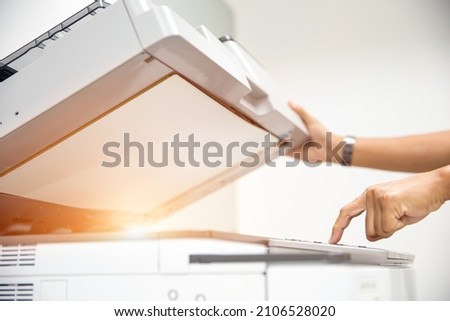 Copier printer, Close up hand office man press copy button on panel to using the copier or photocopier machine for scanning document printing a sheet paper and xerox photocopy. Royalty-Free Stock Photo #2106528020