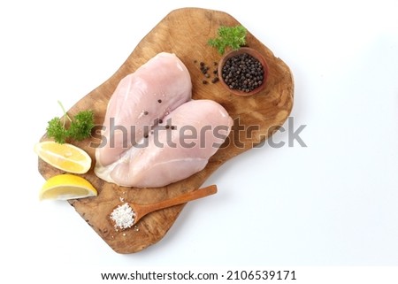top view of Isolated picture of heart shape raw chicken breast fillet no bone on the wooden board with two sliced of lemon, pinch of salt and black pepper 