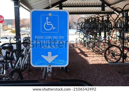 Blue handicapped sign on a bike rack. Please leave this spot open for bicyclists with disabilities