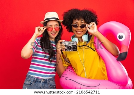 Happy smiling african woman holding flamingo rubber ring and enjoying their summer vacation .Young African American woman isolated on colour red background in vacation with travel .