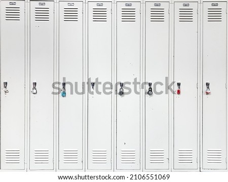 Front view of row of light gray metal lockers with a various key padlocks at close door in fitness, indoor gym, school or university. Public high cabinet for store personal belongings. Security space. Royalty-Free Stock Photo #2106551069