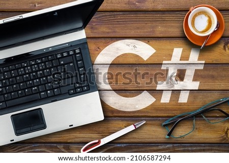 C sharp programming language. C# and laptop, glasses and coffee on wooden table Royalty-Free Stock Photo #2106587294