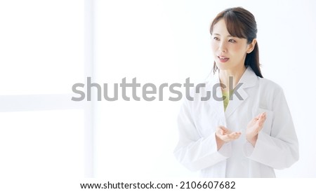 Talking young Asian woman wearing white robe. Interview. Presentation. Royalty-Free Stock Photo #2106607682