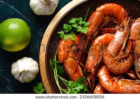 Cooked shrimp and langoustines, king prawns with lime, garlic and parsley. Grilled and fried on dark blue background