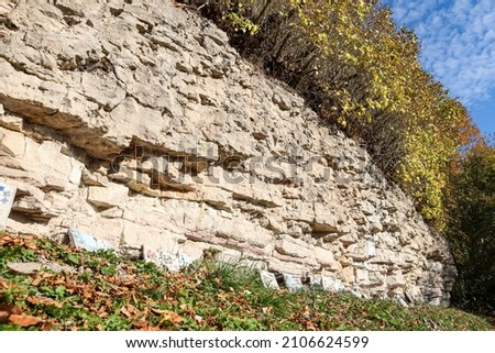 Beautiful natural landscape view of dolomite cliff wall exposure. Photo taken on a warm sunny autumn day with yellow trees.