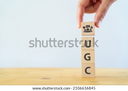 User-generated content concept.(UGC) Online marketing concept. Customer create content on social media . Close up hand put  wooden cube with "UGC" icon and abbreviation on white background,copy space. Royalty-Free Stock Photo #2106636845