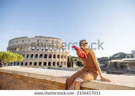 Portrait of a cheerful woman on background of Coliseum in Rome on a summer time. Concept of visiting famous landmarks and travel Italy. Girl wearing dress and colorful shawl Royalty-Free Stock Photo #2106657011