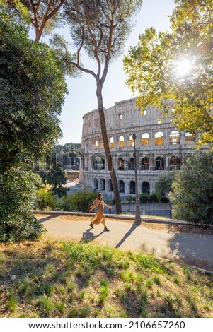 Wide view on coliseum from park near by, small female figure running on path. Landscape of the most famous landmark in Rome Royalty-Free Stock Photo #2106657260