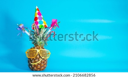 Festive pineapple with a smile in colored decorations, copy space. Congratulations for any holiday