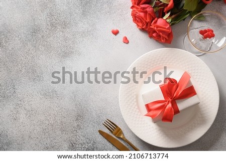 Valentine's day dinner with red roses, romantic gift and red roses on gray background. View from above. Copy space. Royalty-Free Stock Photo #2106713774