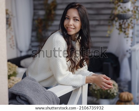 beautiful young woman spends free time outdoors near house on terrace. Autumn sunny lifestyle portrait.