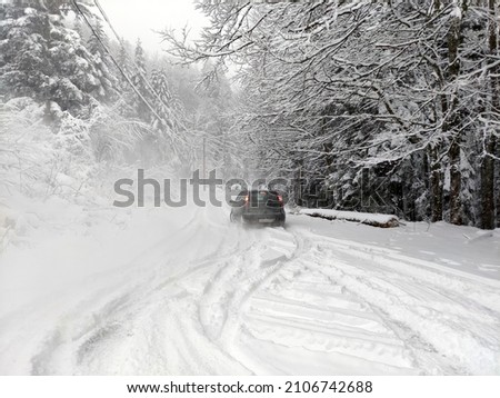 Driving a car in snow and extreme weather conditions. The picture shows a beautiful mountain atmosphere in the harsh and cold winter.