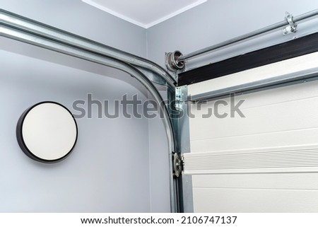 Guiding rails for a home garage door and steel rope drums, view from the inside. Royalty-Free Stock Photo #2106747137