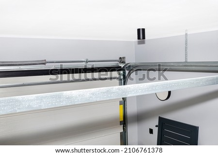 Guiding rails for a home garage door and steel rope drums, view from above. Royalty-Free Stock Photo #2106761378