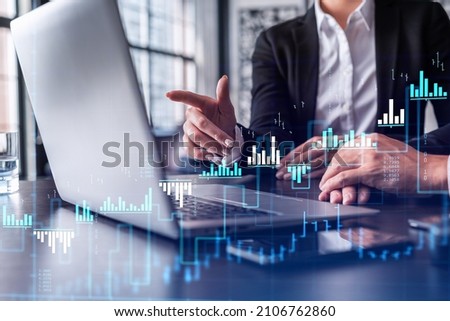 Two traders researching historic data to predict stock market behavior using laptop. Internet trading concept. Forex and financial hologram chart. Forecasting and planning. Royalty-Free Stock Photo #2106762860