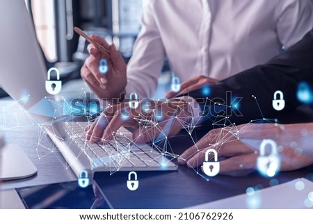 Two businesspeople in formal wear working on the project to protect cyber security of international company using laptop. Padlock Hologram icons. Teamwork concept.