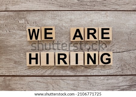 WE'RE HIRING CONCEPT. text on wooden blocks on a wooden background Royalty-Free Stock Photo #2106771725