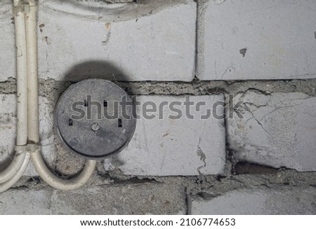 black old dirty electrical outlet on a white brick wall