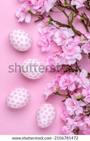 Easter background with polka dot paschal eggs, flat lay with cherry blossom tree branches. Spring season. Minimal design, festive floral greeting card. Pink paper backdrop.