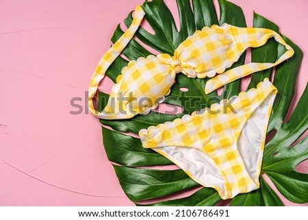 Yellow bikini with monstera leaf on pink background
