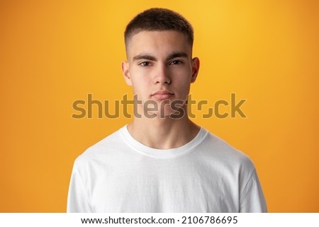 Portrait of a teen boy smiling against yellow background