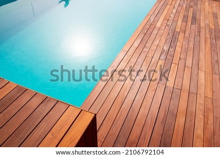 Texture with tiled wooden decorative planking, hardwood ipe pool deck shining sun reflecting on the water Royalty-Free Stock Photo #2106792104