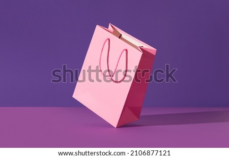 Pink flying paper shopping bag on purple background. Shopping sale delivery concept Royalty-Free Stock Photo #2106877121