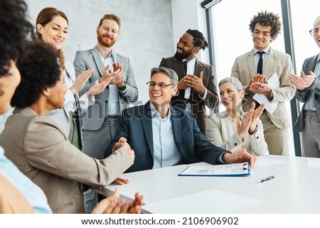Group of happy young and senior business people having a meeting and signing a contract agreement and shaking hands handshake in the office. Teamwork and success concept