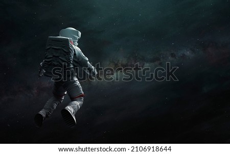 Astronaut at spacewalk looks at Milky Way. Elements of image provided by Nasa Royalty-Free Stock Photo #2106918644