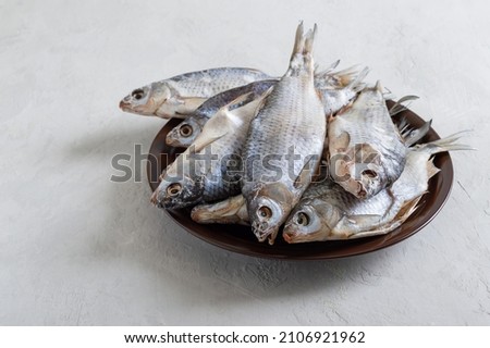 Dried salty river fish in a bowl on a light concrete background.