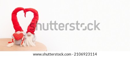 Banner with two gnomes in love in red caps with a heart shape on a white background with copy space