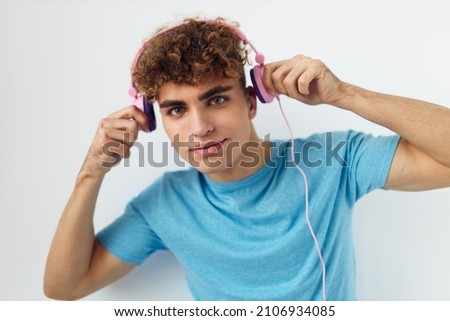 handsome young man in blue t-shirts pink headphones fashion isolated background