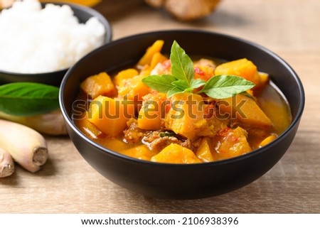 Thai spicy pumpkin curry soup with pork on wooden table