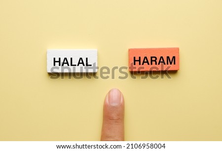 A finger place near the wooden block and written Halal and Haram Royalty-Free Stock Photo #2106958004