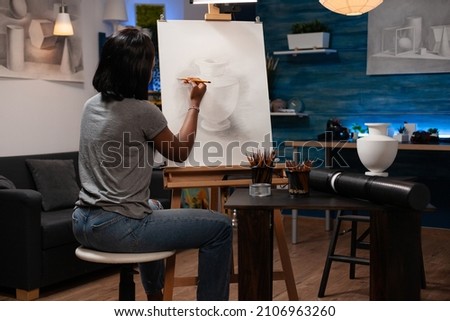 Painter student standing in front of canvas drawing artistic vase structure for art class. Young artist woman painting sketch using professional illustration tools. Concept of creativity paintings Royalty-Free Stock Photo #2106963260