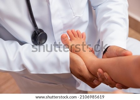 doctor examining children's feet in hospital. Surgeon, traumatologist or orthopedist palpating girl's leg and foot Royalty-Free Stock Photo #2106985619