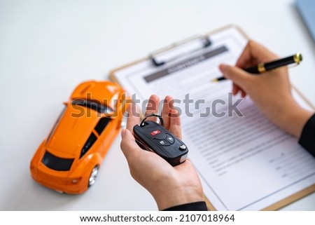Insurance officers hand over the car keys after the tenant. have signed an auto insurance document or a lease or agreement document Buying or selling a new or used car with a car Royalty-Free Stock Photo #2107018964