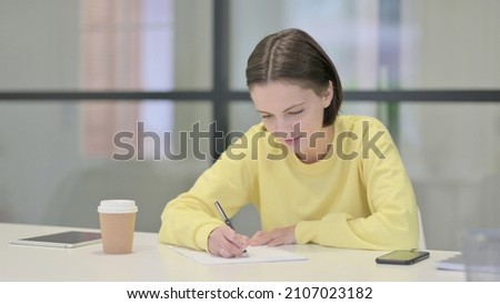 Young Woman Writing on Paper in Office