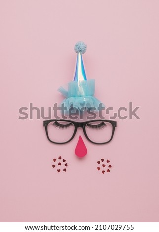 Creative image of a clown on a pink background. The concept of a modern circus. Flat lay.