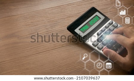 Tax 2022 concept with a hand pressing a calculator and virtual icon.