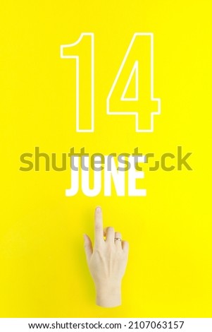 June 14th. Day 14 of month, Calendar date.Hand finger pointing at a calendar date on yellow background.Summer month, day of the year concept