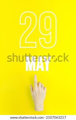 May 29th. Day 29 of month, Calendar date.Hand finger pointing at a calendar date on yellow background.Spring month, day of the year concept