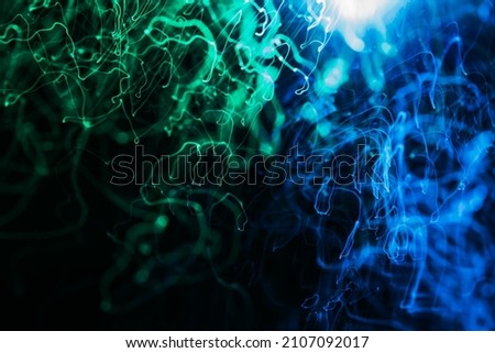 Abstract background in neon blue and green tones. long exposure of lights sparks and blowing. festive background. Sparkling magical dust particles.
