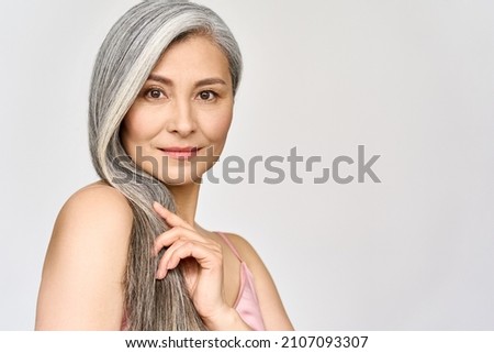 Portrait of gorgeous happy middle aged mature asian woman, senior older 50s lady pampering her hair looking at camera isolated on white. Ads of anti age skin and hair care spa. Copy space. Royalty-Free Stock Photo #2107093307