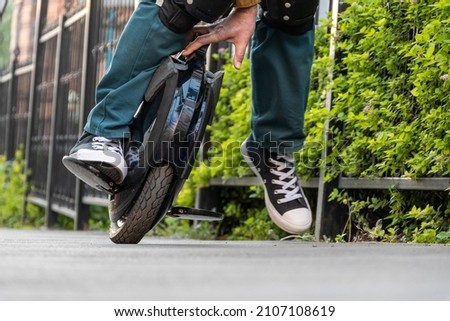 Riding an electric unicycle (EUC). A rider in protective knee pads falls from an e-monowheel. Royalty-Free Stock Photo #2107108619