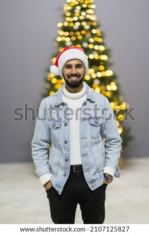 Self portrait of cheerful excited enjoying man having finished decorating his christmas tree in santa cap
