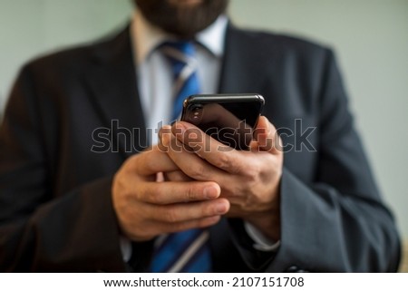 Male hand holding smartphone reads QR Coder, business suit and tie with mobile in hand, copy space on background.   