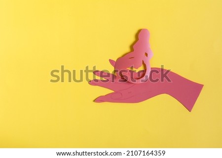 Minimalistic painting depicting a hand holding a person in a wheelchair bright yellow background. Social and household protection of people with disabilities